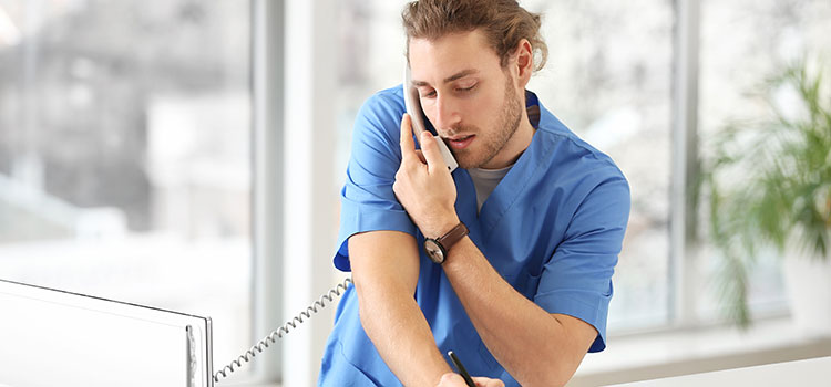 busy medical assistant answers phones at clinic front desk