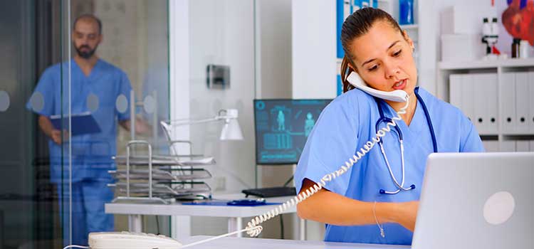 medical assistant in scrubs logs in lab results given over the telephone