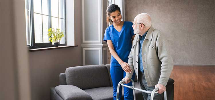 a certified nursing assistant helps an elderly patient ambulate using a walker