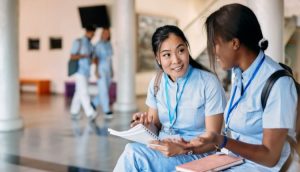 two medical assistant students sit and talk on campus together